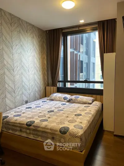 Cozy bedroom with modern decor and large window offering natural light.