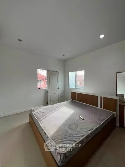 Spacious bedroom with natural light and modern design, featuring a large bed and minimalist decor.
