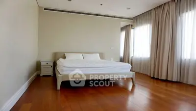 Spacious bedroom with wooden flooring and large windows in modern apartment