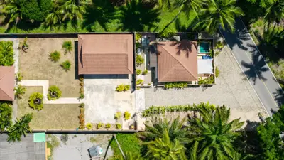 Aerial view of tropical property with lush greenery and two houses, ideal for serene living.