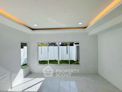 Spacious modern living room with large windows and elegant ceiling lighting.