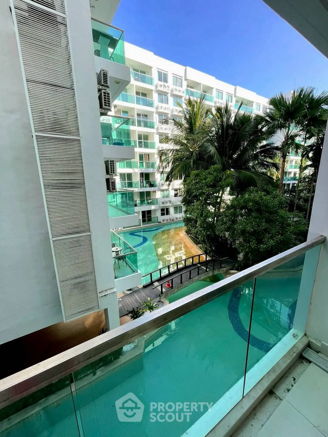 Modern apartment building with pool view and lush greenery from balcony.