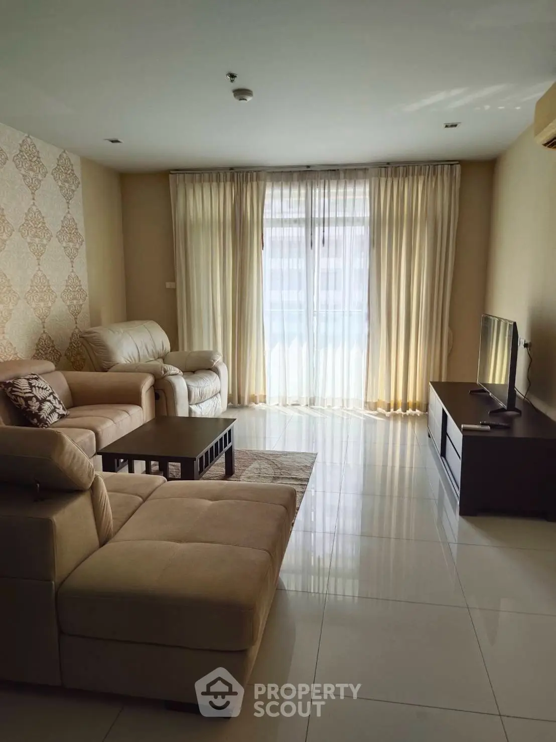 Spacious living room with elegant decor and natural light, featuring a comfortable sofa and modern TV setup.