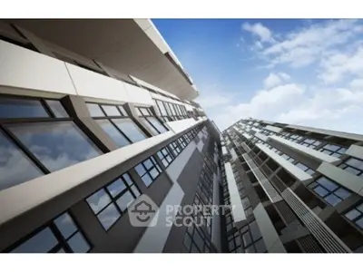 Modern high-rise building with sleek architectural design and expansive glass windows against a blue sky.
