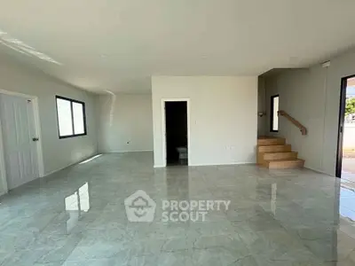 Spacious open-plan living area with modern tiled flooring and natural light.