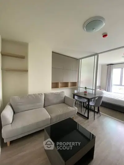Modern apartment interior with cozy living room and bedroom, featuring sleek furniture and natural light.