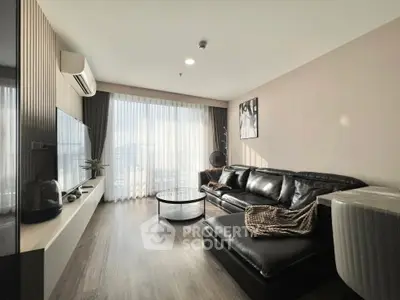 Modern living room with sleek black leather sofa and large window view.