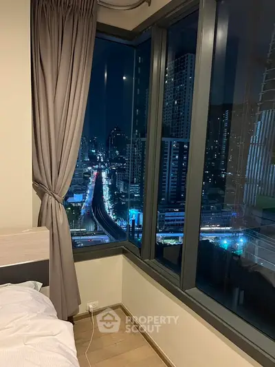 Stunning city view from a modern bedroom with floor-to-ceiling windows and elegant curtains.
