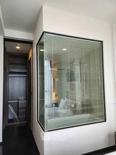 Modern bathroom with glass partition and walk-in closet in luxury apartment.