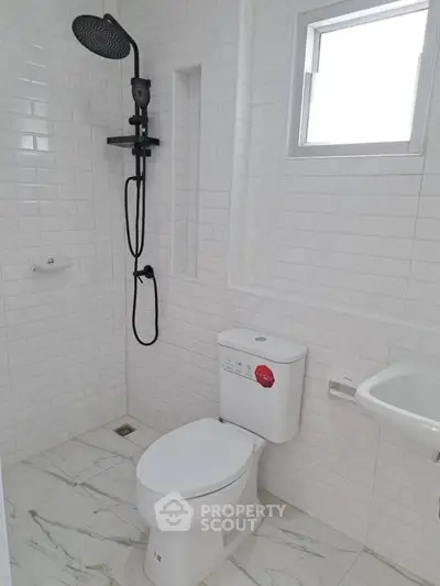Modern minimalist bathroom with white tiles and sleek shower design.