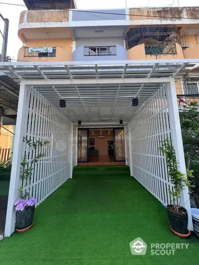 Charming house entrance with green artificial turf and modern pergola design.