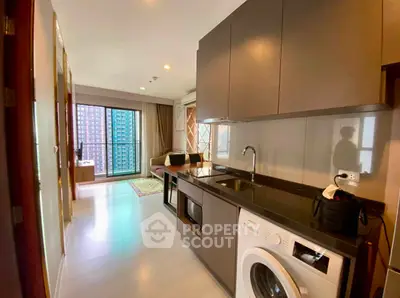 Modern apartment interior with open kitchen and living area, featuring a washing machine and balcony view.