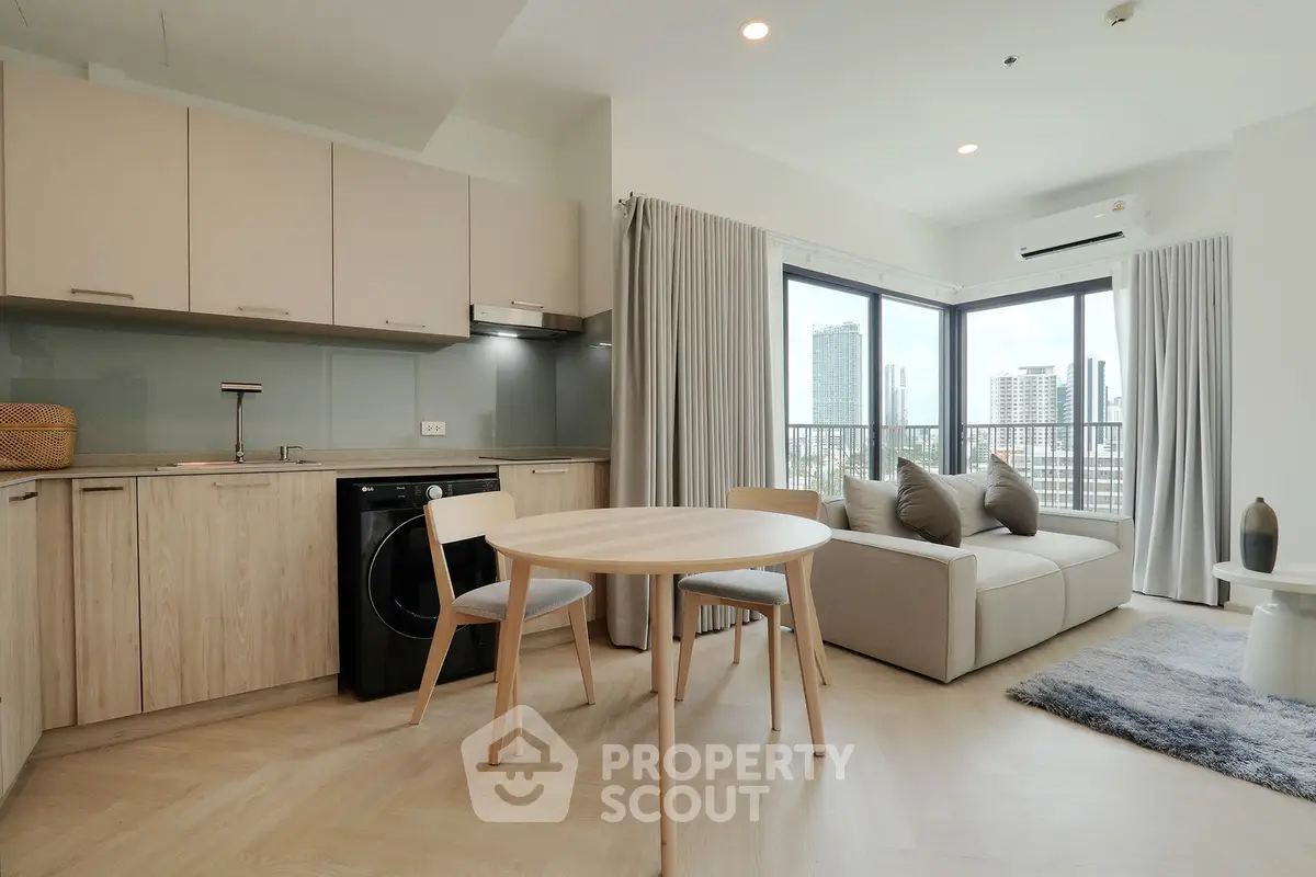 Modern open-plan living room with kitchen, featuring sleek design and city view.