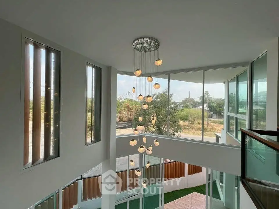 Stunning modern home with large windows and elegant chandelier, offering abundant natural light and scenic views.