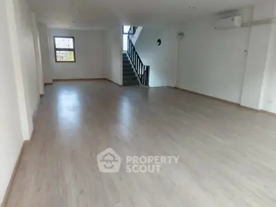 Spacious open-plan living area with wooden flooring and staircase, ideal for modern living.