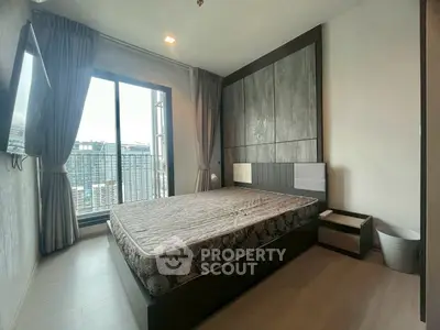 Modern bedroom with large window and city view, featuring stylish decor and ample natural light.