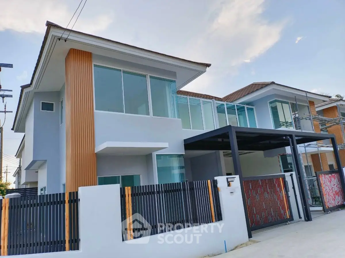 Modern two-story house with large windows and sleek design in a suburban neighborhood.