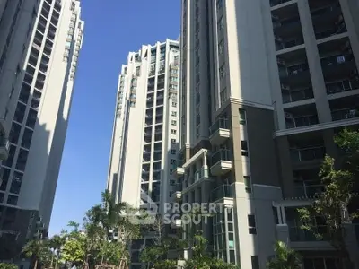 Modern high-rise residential buildings with lush greenery and clear blue sky.