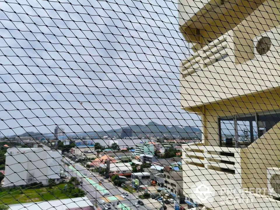 Stunning cityscape view from a high-rise balcony with safety netting