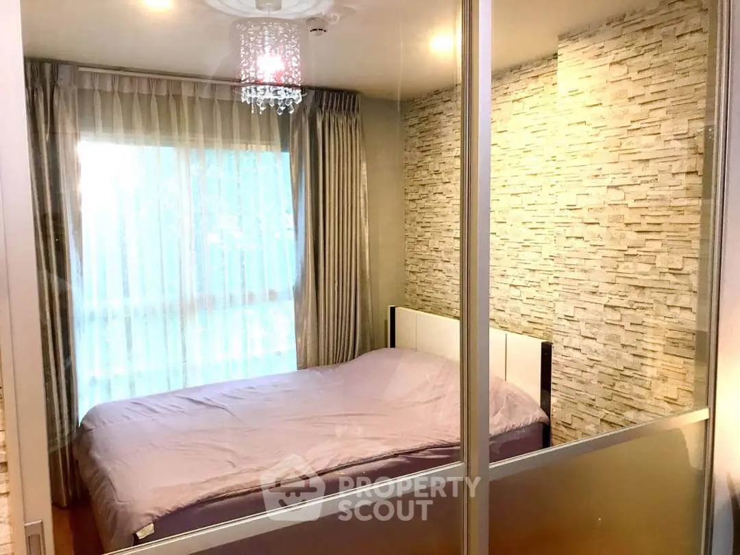 Cozy bedroom with stone accent wall and elegant chandelier lighting