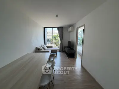 Modern living room with sleek furniture and large window offering natural light and city view.