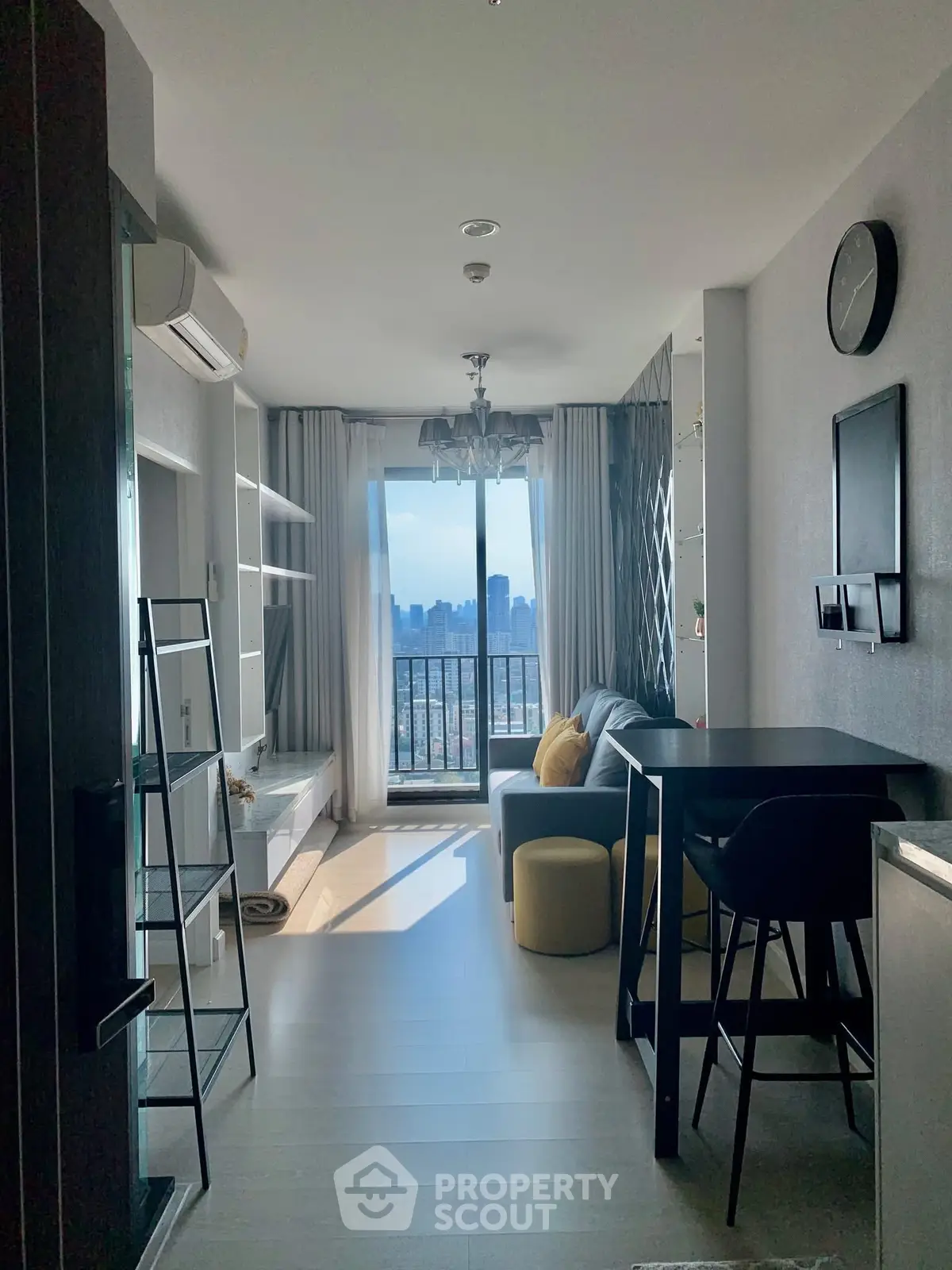 Modern living room with city view, stylish decor, and balcony access in a high-rise apartment.