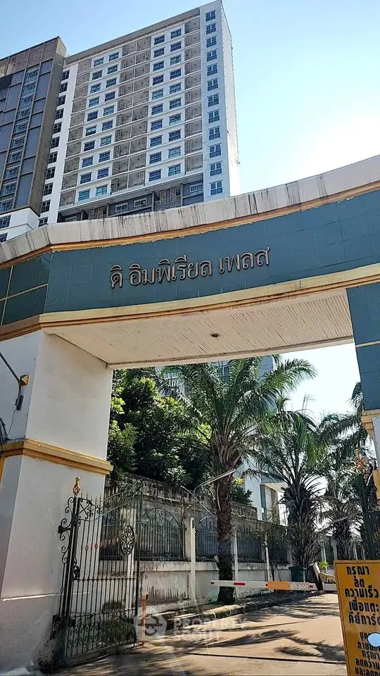 Stunning entrance of a modern high-rise building with lush palm trees and clear blue sky.