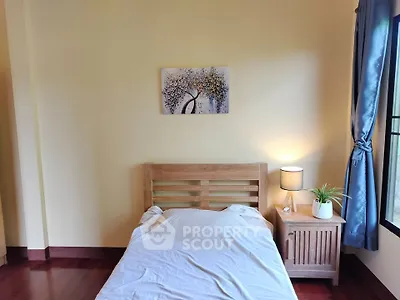Cozy bedroom with wooden bed frame and nightstand, soft lighting, and window view.