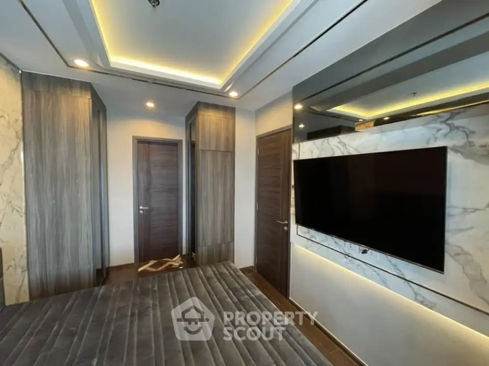 Modern bedroom with sleek design and wall-mounted TV in luxury apartment.