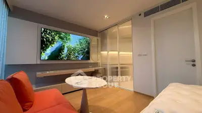 Modern living room with sleek design, featuring a large TV, stylish furniture, and wooden flooring.