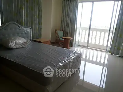 Spacious bedroom with large windows and balcony access, featuring modern decor and natural light.