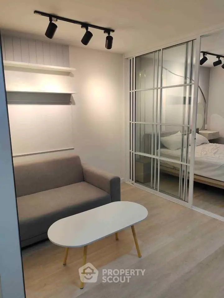 Modern living room with sleek design and cozy sofa adjacent to a bedroom.