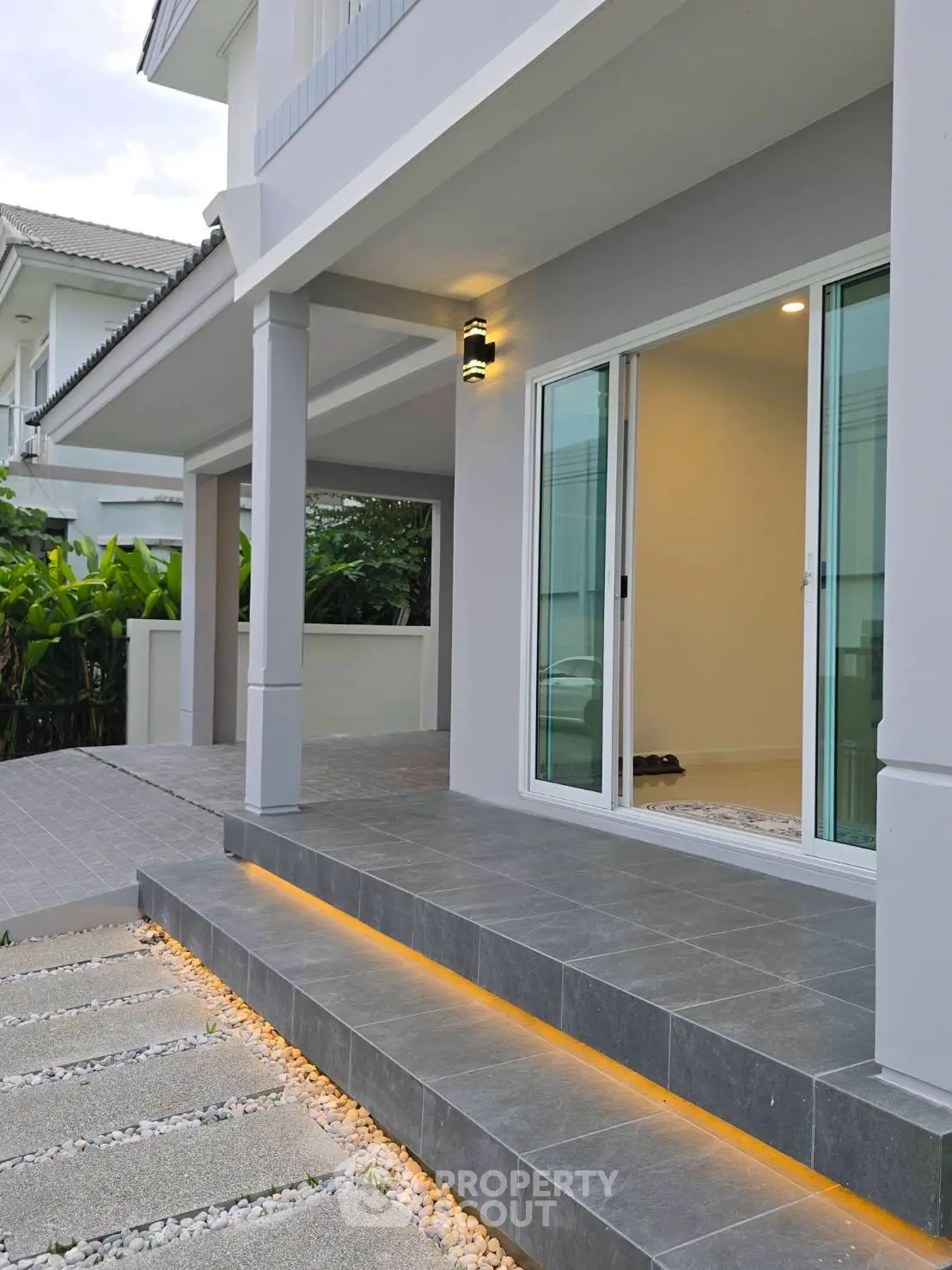 Modern exterior of a stylish home with sleek gray tiles and ambient lighting on steps.