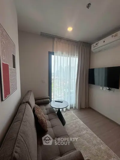 Cozy living room with modern decor, featuring a plush sofa, wall-mounted TV, and large window with city view.