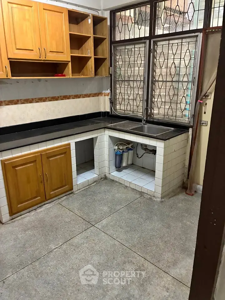 Spacious kitchen with wooden cabinets and large windows, perfect for culinary enthusiasts.