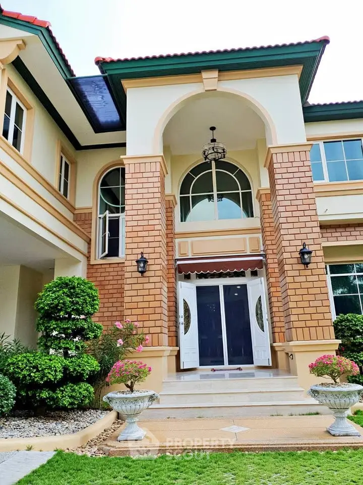 Stunning two-story home with elegant brick facade and grand entrance, surrounded by lush landscaping.