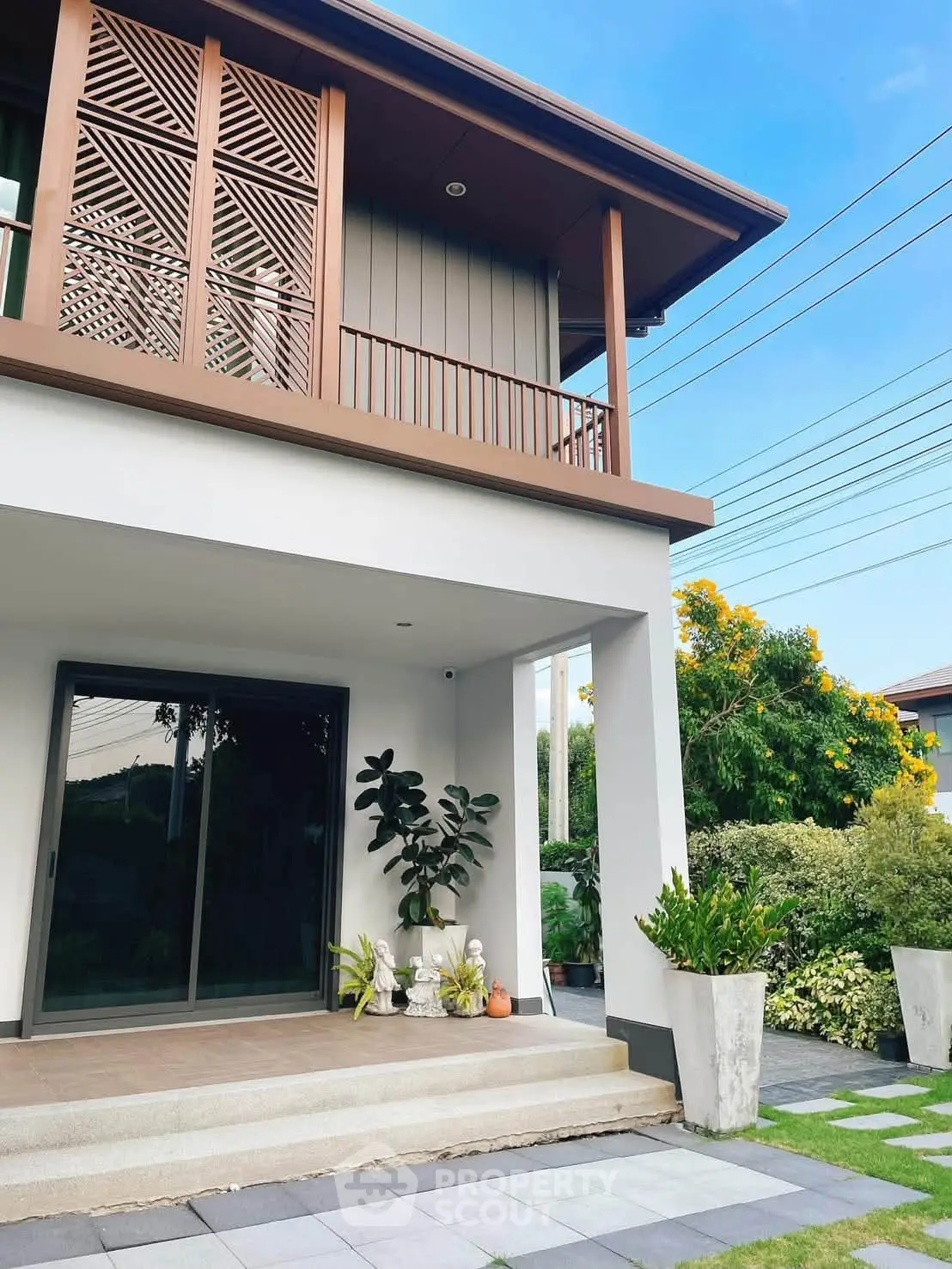Modern two-story house with stylish balcony and lush garden, perfect for serene living.