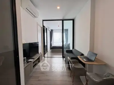 Modern apartment interior with open living room and bedroom, featuring sleek furniture and natural light.