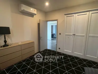 Spacious bedroom with modern furniture and air conditioning unit, featuring a stylish carpet and ample storage.