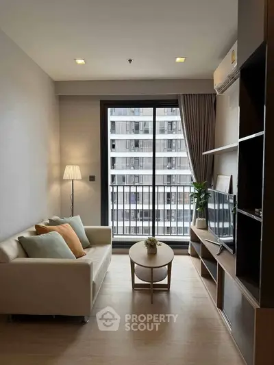 Modern living room with cozy sofa, stylish decor, and large window offering city view.