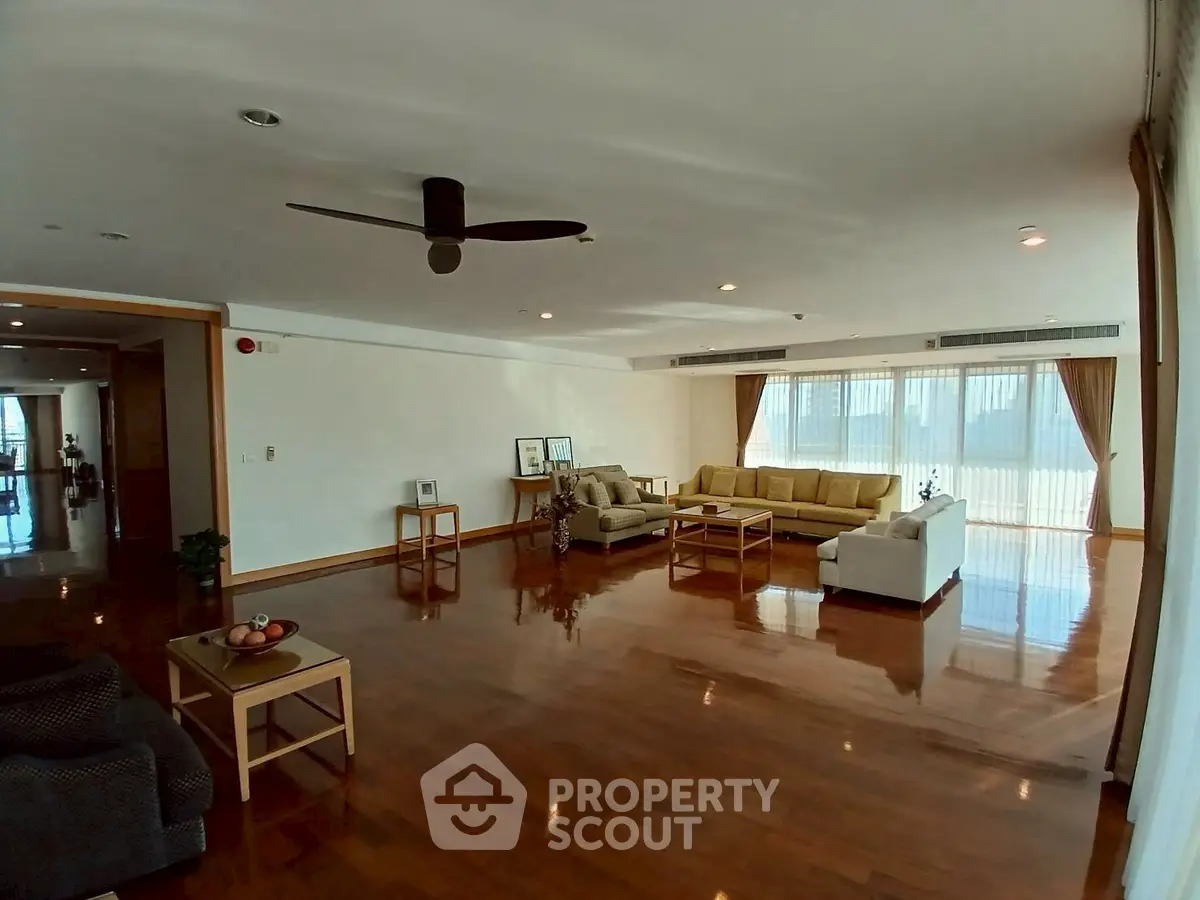 Spacious living room with elegant wooden flooring and modern furniture, perfect for family gatherings.