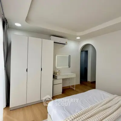 Modern bedroom with sleek design, featuring a wardrobe, vanity, and cozy bed in a bright space.