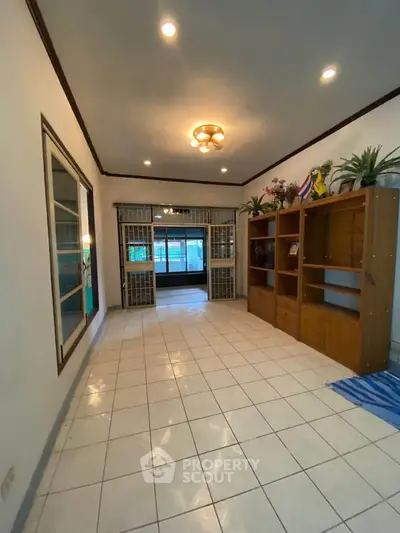 Spacious tiled living area with wooden shelving and decorative lighting.