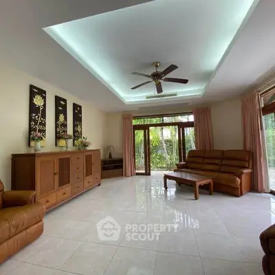 Spacious living room with elegant decor and garden view, featuring comfortable seating and natural light.