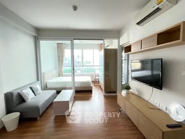 Modern living room with sleek design and natural light, featuring a cozy bedroom view.