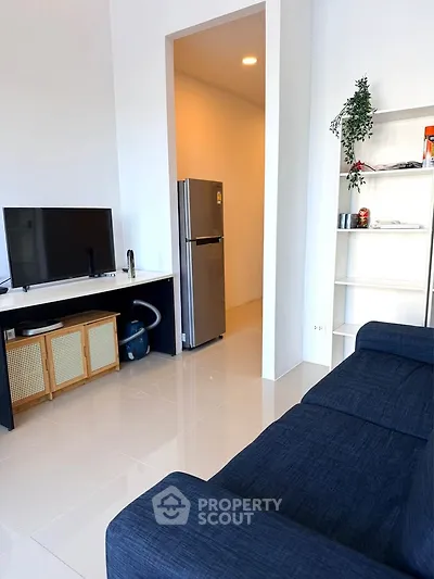 Modern living room with sleek furniture and stainless steel fridge, perfect for urban living.