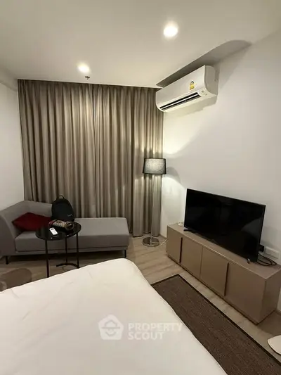 Modern bedroom with cozy seating area and air conditioning, perfect for relaxation.