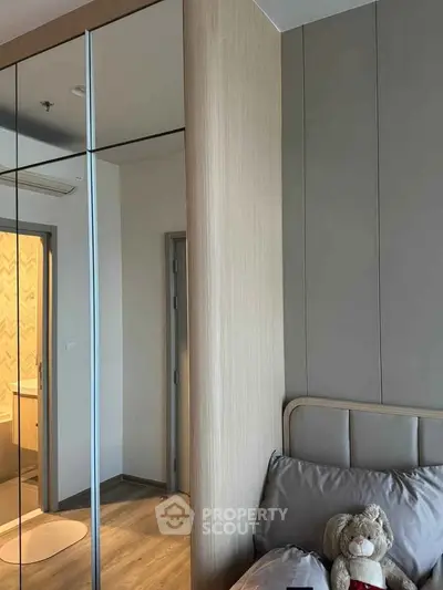 Modern bedroom with mirrored wardrobe and cozy bedding in stylish apartment.