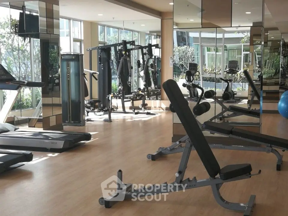 Spacious modern gym with state-of-the-art equipment and mirrored walls in a luxury residential complex.