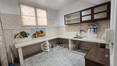 Spacious kitchen with tiled walls and countertops, featuring a water filtration system and ample storage space.